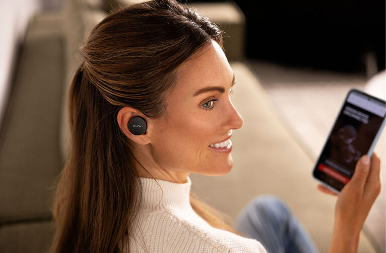 A woman listening to Denon PerLs