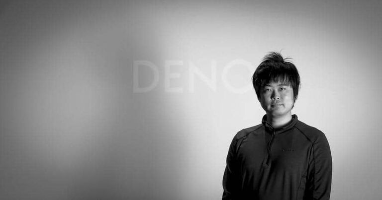 A man standing in front of Denon logo