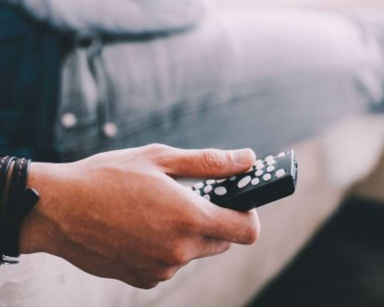 A person pressing buttons on a remote