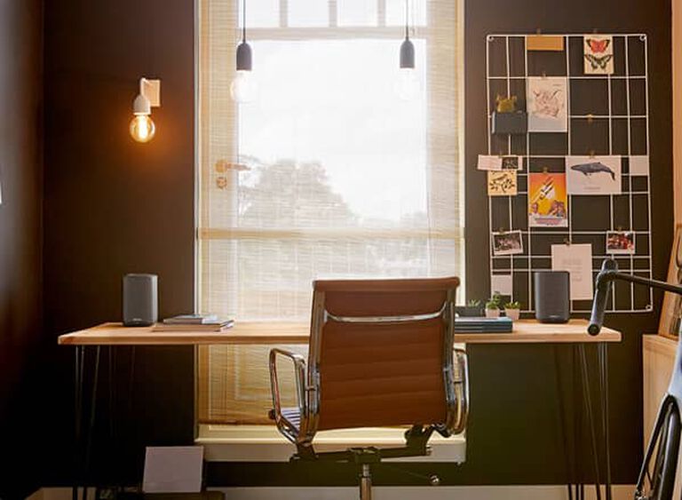 A desk with Denon Home speakers