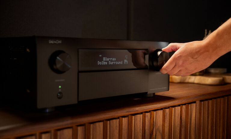 A man changing the volume on an AVR