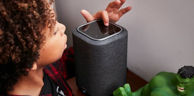 A boy touching the buttons on a Denon Home Speaker