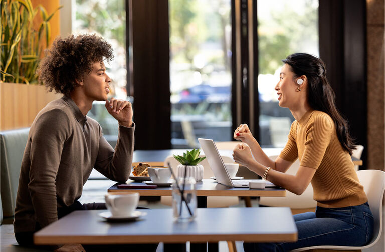A couple with headphones in, talking at a table