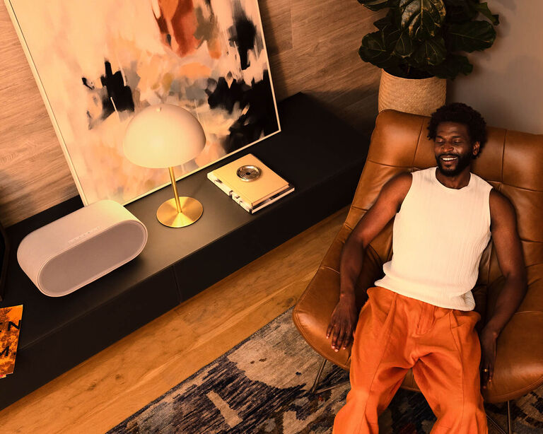 A man laying in a chair listening on a Denon Home 600