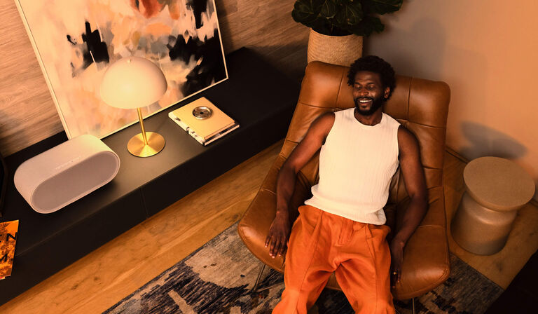 a man laying back in a chair listening on a Denon Home 600