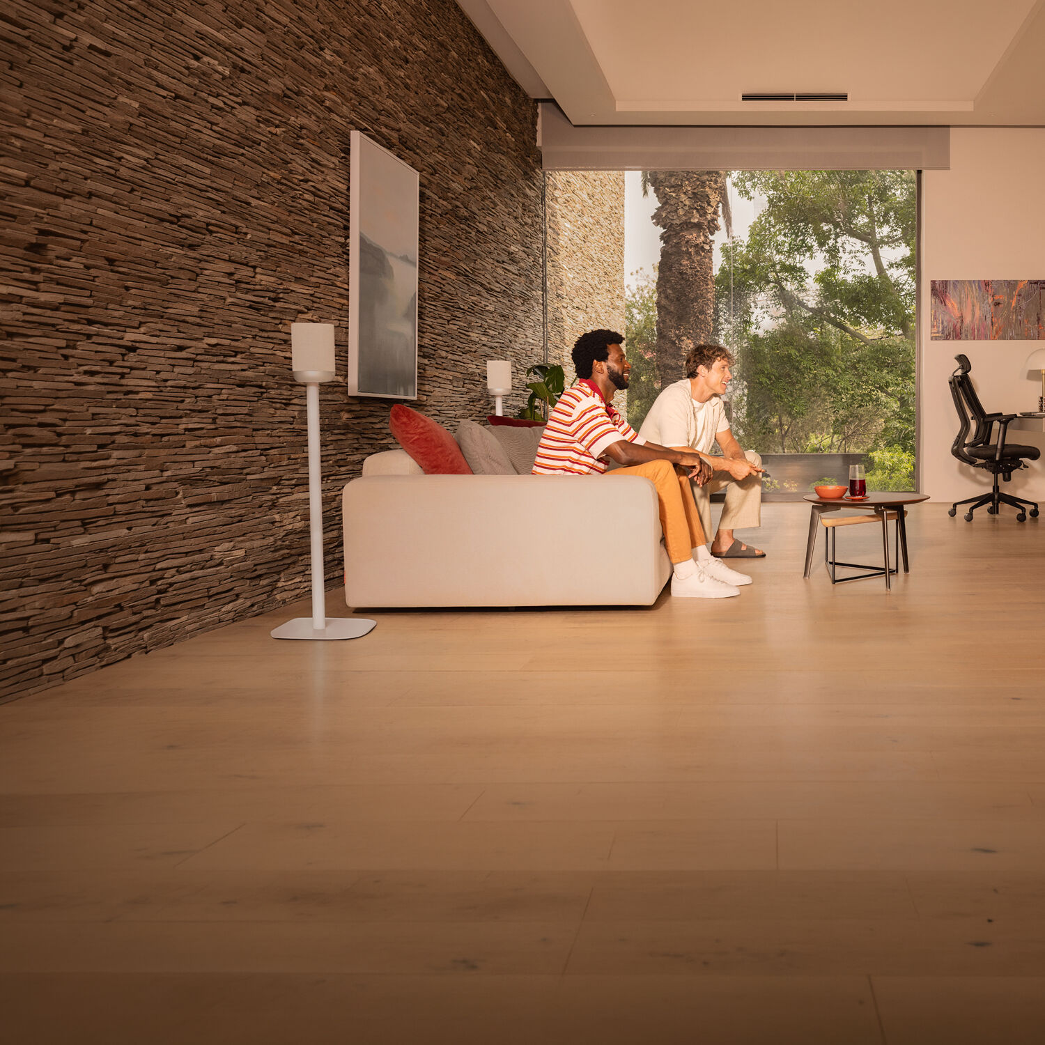 Two men watching a TV surrounded by a wireless home theater